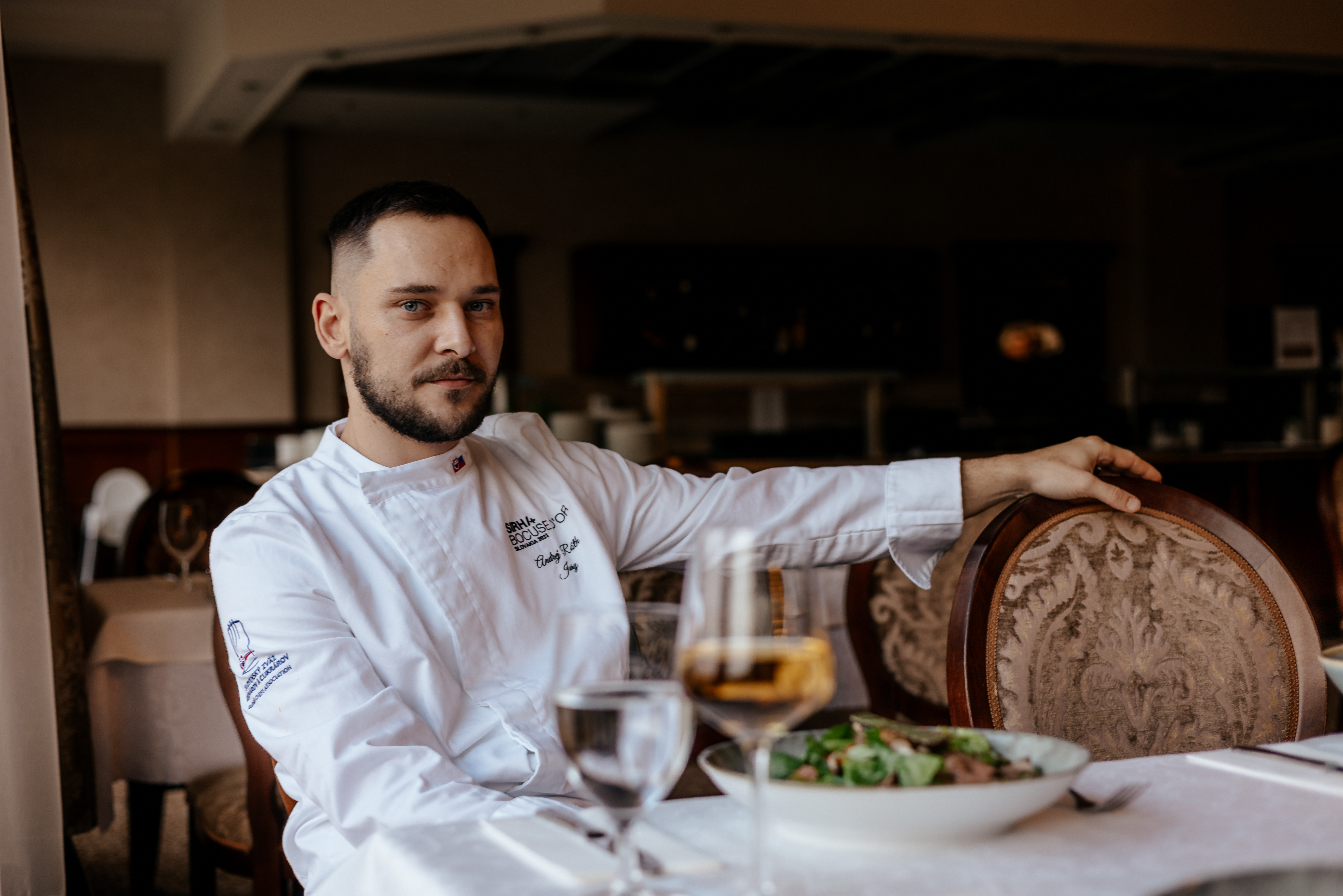 a chef sitting at a table with food and drinks